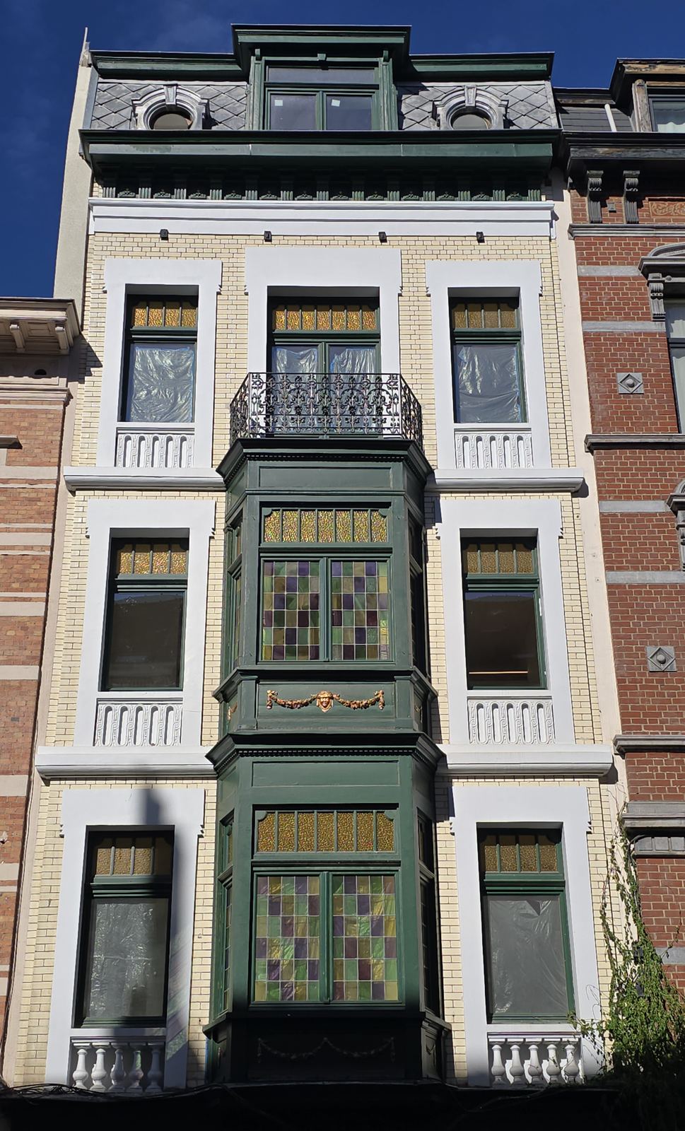Façade of Rue de Mérode 385 with a green oriel and coloured stained glass